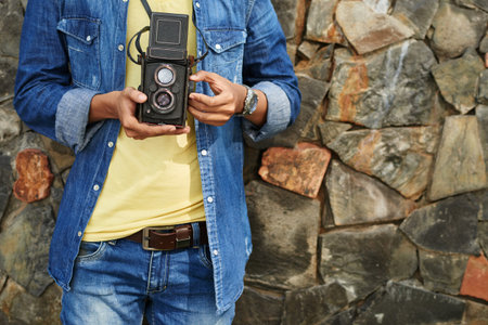Cropped image of guy taking photos with retro camera