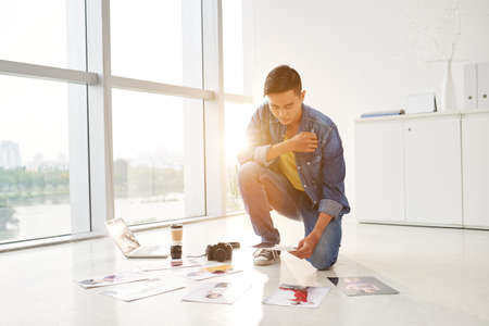 Vietnamese photographer looking at photos spread out on the floorの写真素材