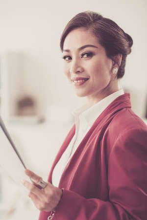 Beautiful smiling Vietnamese business lady with document in her handの写真素材