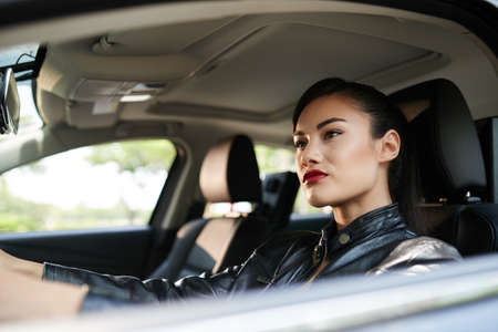 Stylish woman in leather jacket driving carの写真素材