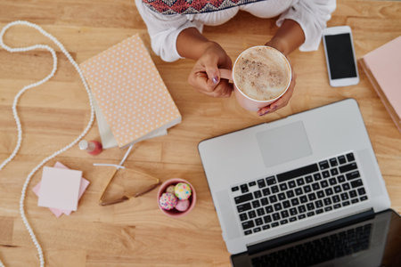 Woman drinking coffee when working on laptop, view from top