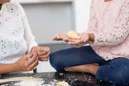 Girl holding croissant she cooked for the first timeの写真素材