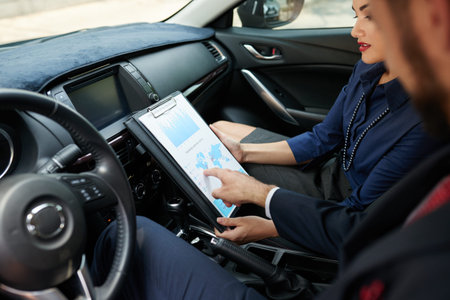 Business people analyzing chart when sitting in carの写真素材
