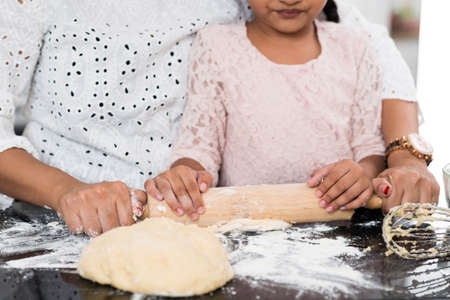 Cropped image of mother and daughter rolling out doughの写真素材