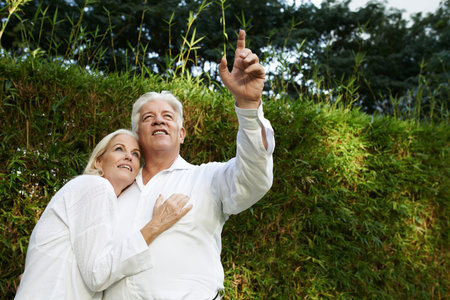 Mature man showing something in the sky to his wife
