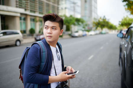Portrait of Vietnamese young photographer with smartphone standing in streetの写真素材