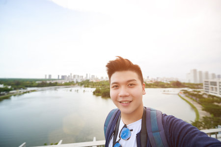 Joyful young man photographing against city river
