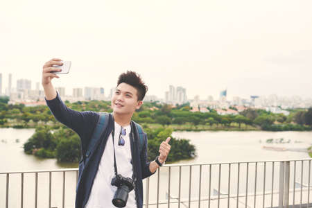 Young Asian man taking selfie on the background of big cityの写真素材