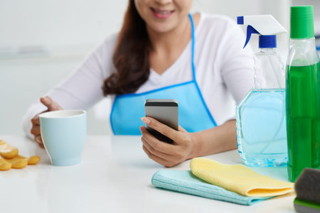 Housewife drinking tea and checking new in her smartphoneの写真素材