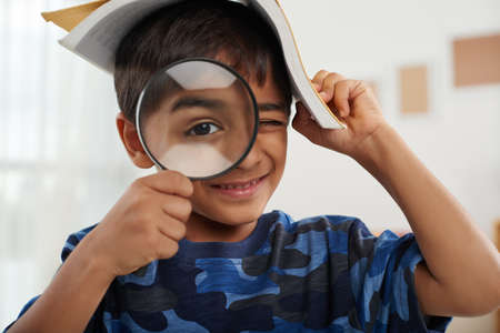 Boy with a book looking through magnifying glassの写真素材