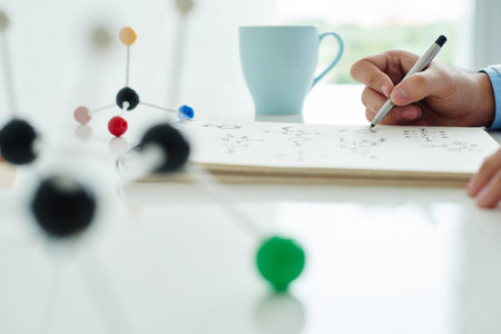 Close-up of researcher writing formulas at the table