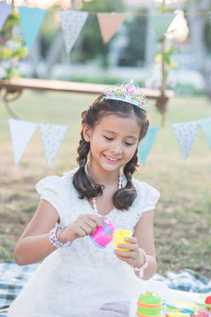 Smiling girl playing with plastic tea service outdoorsの写真素材