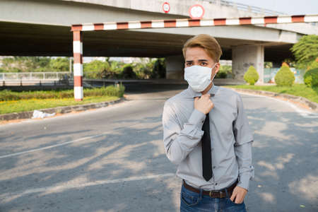 Young Asian man with mask on his face standing in the streetの写真素材