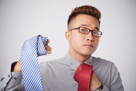 Portrait of Asian businessman choosing perfect tieの写真素材