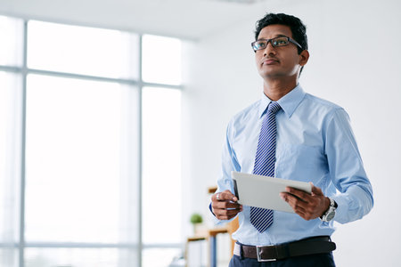 Young Indian business executive holding tablet computer