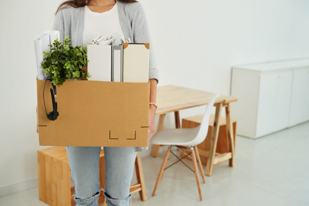 Cropped image of employee with cardboard box of her belongings