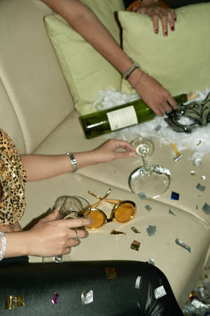 Sparkles, glasses and wine bottle on sofa at the partyの写真素材