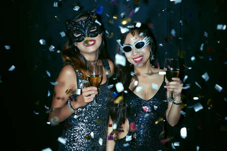 Two young women in masks dancing at the partyの写真素材