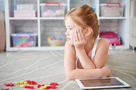 Pensive girl with tablet resting on floor