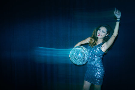 Party girl with disco ball dancing in the darkの写真素材