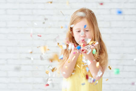 Little girl blowing out confetti in in her handsの写真素材