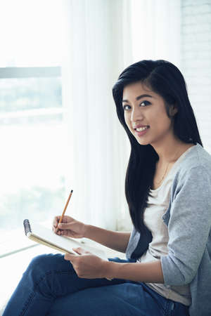 Lovely girl drawing with pencil in her albumの写真素材