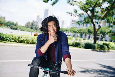 Joyful young man enjoying cycling in the cityの写真素材