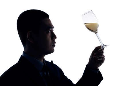 Silhouette of business person looking at glass of wine in his handsの写真素材