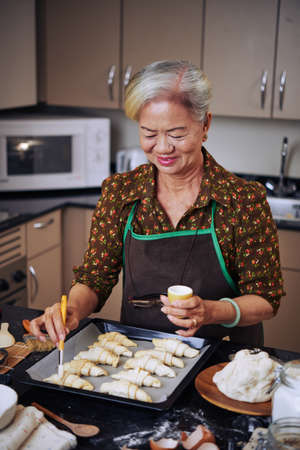 Smiling VIetnamese woman cooking croissants in the morningの写真素材
