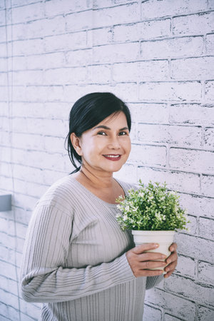 Portrait of senior Asian woman holding flower potの写真素材