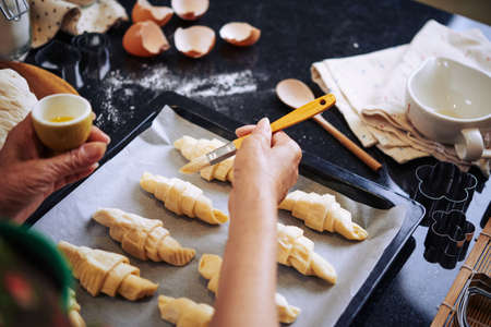 Hand of woman covering croissants with yolkの写真素材