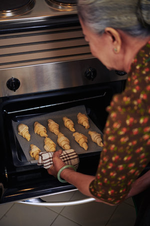 Senior woman baking french croissants, rear viewの写真素材