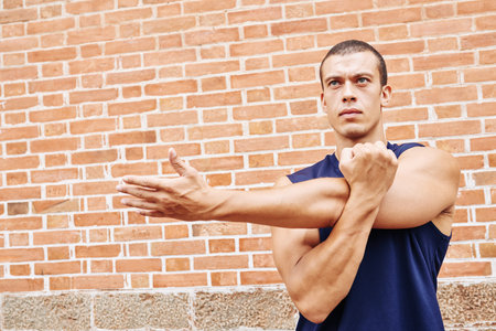 Concentrated young sportsman doing exercise for armsの写真素材