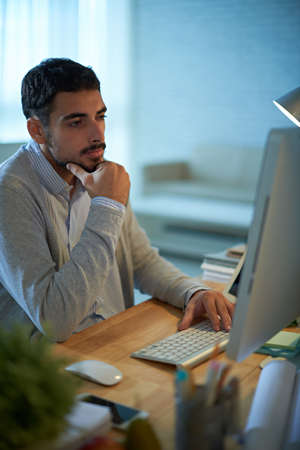 Handsome pensive programmer coding in the officeの写真素材