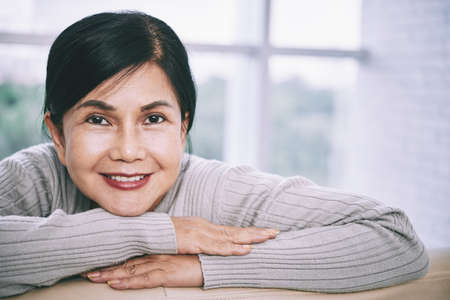 Cheerful mature Asian lady smiling at cameraの写真素材