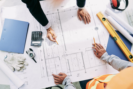 Engineer and architect analyzing blueprint, view from aboveの写真素材