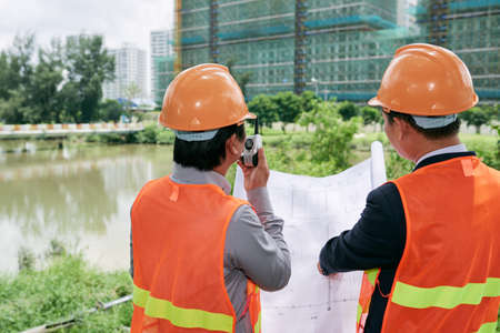 Contractor using walkie-talkie when working on construction siteの写真素材