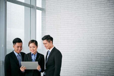 Young business people reading information on screen of tabletの写真素材