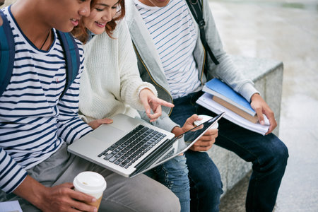Cropped image of college students watching something on laptop