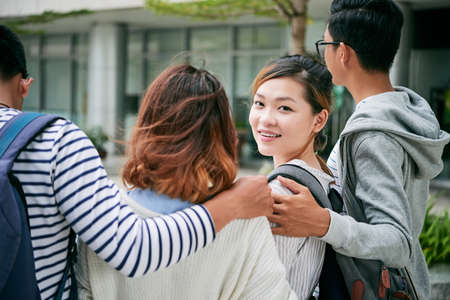 Lovely college girl smiling at camera when walking with friendsの写真素材
