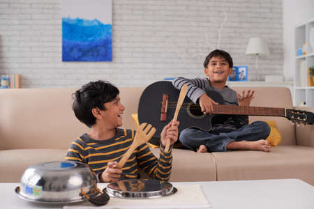 Indian kids enjoying playing instruments at homeの写真素材
