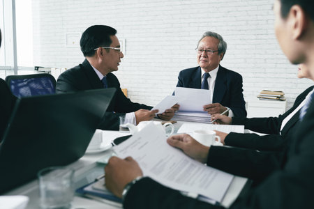 Team of Asian prosecutors discussing case at table