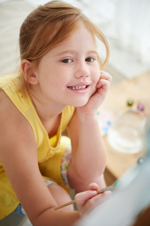 Inspired smiling little girl painting on canvasの写真素材