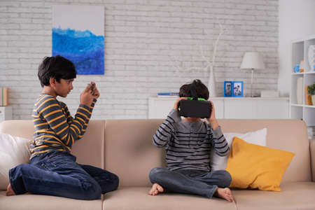 Indian boy photographing his brother in VR gogglesの写真素材
