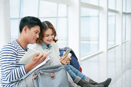 Vietnamese couple sitting on university floor and reading bookの写真素材