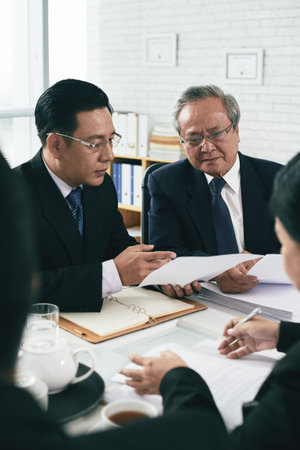 Mature Vietnamese lawyer consulting his younger colleague