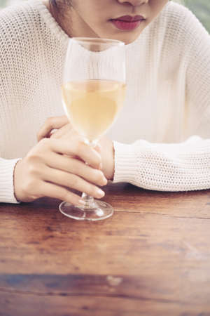 Young woman sitting at table and drinking white wineの写真素材