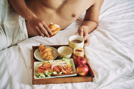 Tray with healthy breakfast on bed of manの写真素材