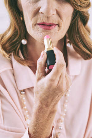 Cropped image of senior woman applying lipstickの写真素材