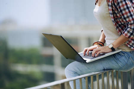 Cropped image of woman working on laptop outdoors, side viewの写真素材